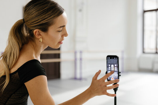 Dancer tapping screen of smartphone to adjust it for creating video 