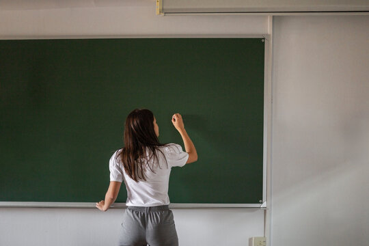 female student next to a blackboard in class - Powered by Adobe