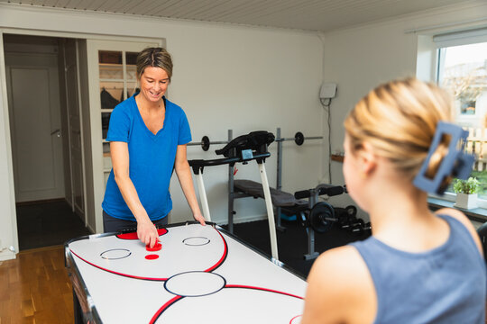 Mother and Daughter Playing Air Hockey in Basement Game Room