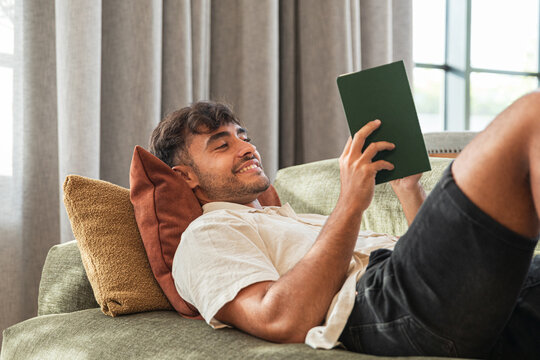 Man reading a book relaxed on his couch
