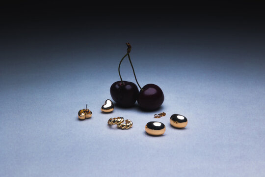 Cherries with Golden Jewelry Against a Blue dark Backdrop