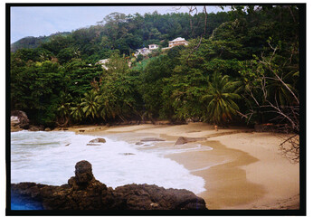 Tropical beach landscape viewed from coastal rocks in daylight