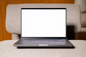 Mockup Laptop with White Screen on Armchair at modern office 