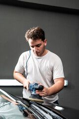 Hombre puliendo pintura de automovil con pulidora y pasta de pulir para dar brillo