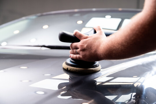 Hombre puliendo pintura de automovil con pulidora y pasta de pulir para dar brillo