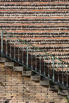 Intricate Pattern Brick Wall with Round Stones and Metal Stair Railing