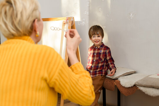 Mother and autistic child playing with soap bubbles