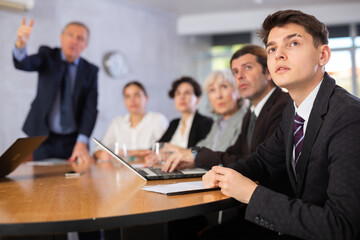 Male top manager standing and confidently speaking during corporate meeting using hand gestures