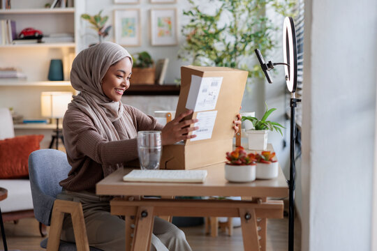 Excited woman opening package on table at home