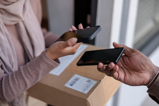 Woman receiving parcel and doing mobile payment 