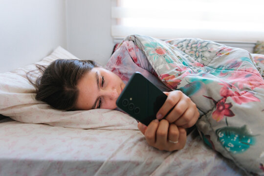 Young woman checking smartphone first thing in the morning 