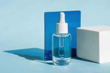 Transparent dropper bottle with white cap is set against light blue background with bold blue...