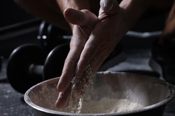 Man applying talcum powder onto his hands above bowl before training in gym, closeup