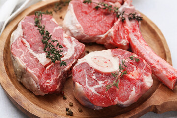 Pieces of raw beef and spices on light grey table, closeup
