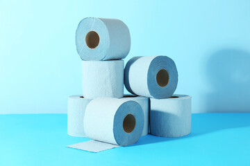 Stack of light blue toilet paper rolls on color background