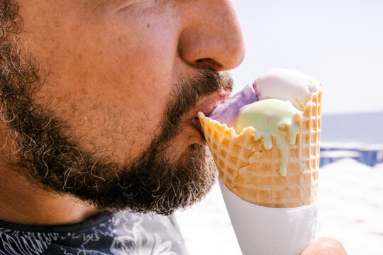 A man eats ice cream on the beach on a sunny day