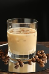 Coffee cream liqueur in glass and beans on table, closeup