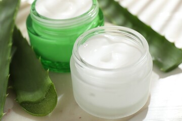 Cream and aloe leaves on light background, closeup