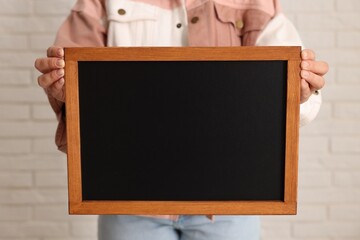 Woman holding blank small blackboard indoors, closeup