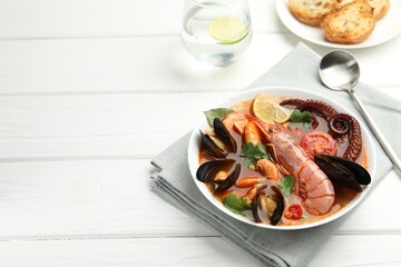 Delicious seafood soup served on white wooden table. Space for text