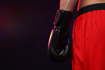 Man in boxing glove on dark background, closeup. Space for text