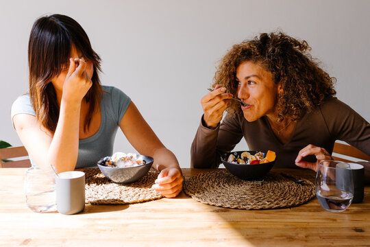 Multiracial friends share quality time while enjoying a bowl of fruit