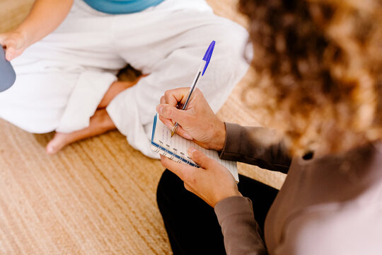 Anonymous woman writing handwritten notes in a notebook with a friend