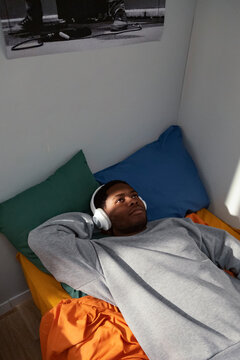 Young man relaxing on bed listening to music with headphones 