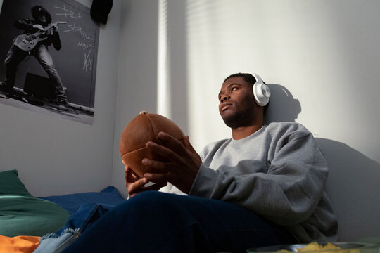 Young student relaxing in dorm room listening to music