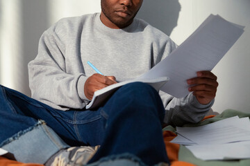 Concentrated student taking notes and reading documents on bed