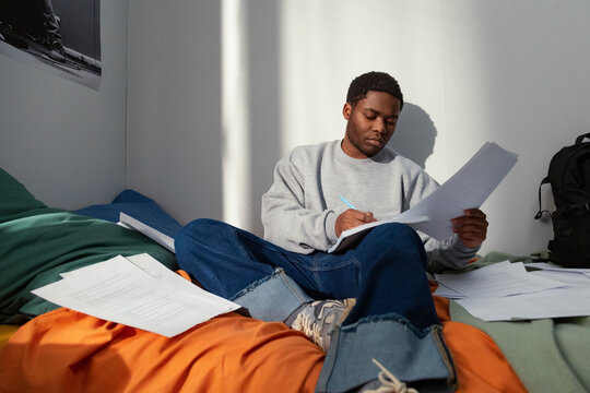 Focused student studying and taking notes in dorm room after school