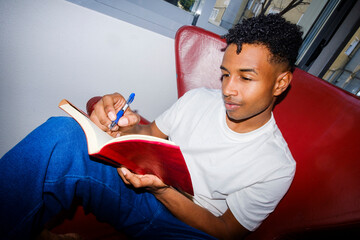Young man at home writing journal. Direct flash. Wide angle.