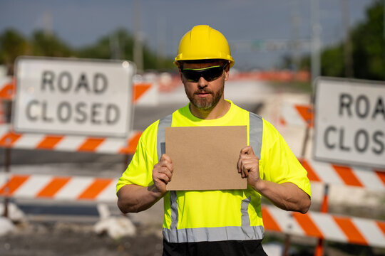 No trespassing. Construction worker with outstretched hand showing stop gesture warning. Stop sign in hands of worker. Concept he warns of danger. An engineer holds up an empty billboard near roadwork