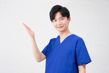 医者・看護師・歯科医師・介護士　左側を手のひらで指す男性　白背景