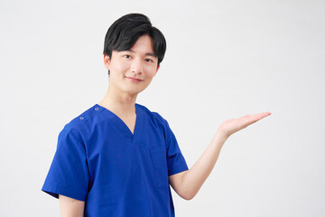 医者・看護師・歯科医師・介護士　右側を手のひらで指す男性　白背景