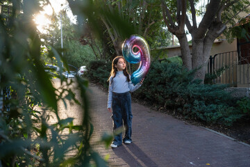 Child Holding Colorful Balloon on a Sunny Day in the Park