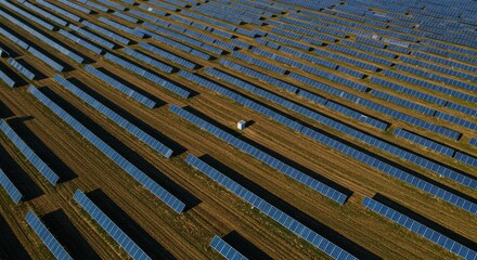 Obraz premium Aerial View of a Expansive Solar Farm with Rows of Solar Panels Under a Clear Sky in a Rural Area