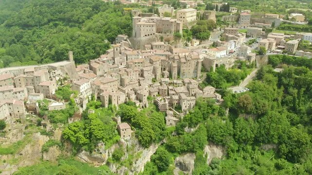 Aerial summer afternoon view of Sorano. Rooftops of an ancient medieval hill town hanging from a tuff stone over the Lente River. Etruscan heritage. Province Grosseto, Tuscany, Italy.