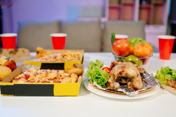 Mouth watering pizza, roasted chicken, fresh fruits, and drinks on a table. Perfect for food celebrations, gatherings,