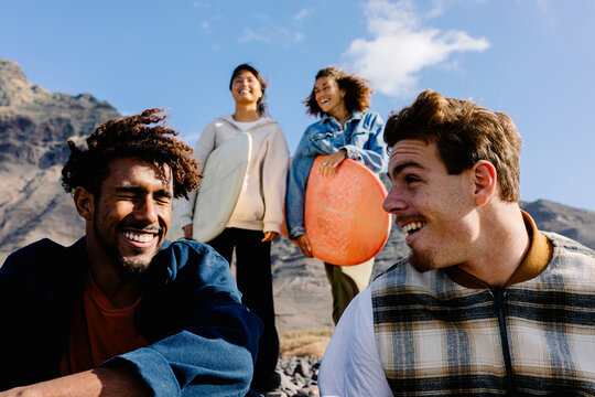 Diverse surfing enthusiasts gazing at the ocean during a sunny day