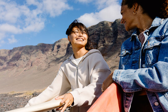A mid-range shot with copy space of two female surfers passing time