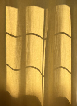 Warm sunlight filtering through textured curtains creates soft shadows