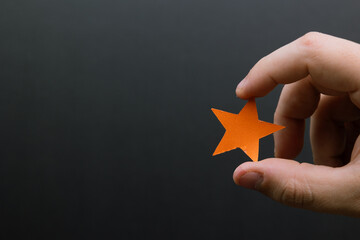 Hand holding an orange star. Symbolizing creativity, dreams, hope, imagination, inspiration.
