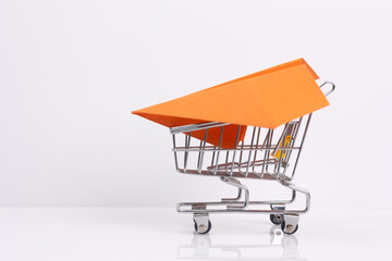 Shopping cart with red paper airplane symbolizing online purchases, delivery and increased sales