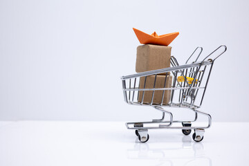 Shopping cart with packages and origami boat. Symbolizing e-commerce, modern commerce, sale and export.