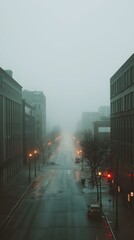 Foggy city street scene at dawn.  Empty road with buildings on either side. Car parked. Moody atmosphere.
