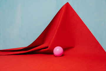 Pink Balloon on Red Fabric Against a Soft Blue Background