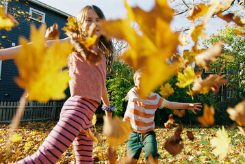 Film photo of kids playing with fallen leaves in their backyard