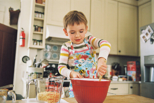 Film photo of child wearing apron baking in the kitchen at home
