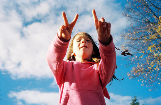 Happy child playing outside holds up three fingers